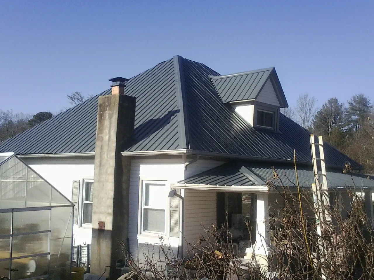 Dark blue standing seam metal roof on a white farmhouse with dormer — Slate & Tile Roof Repair by Roofing Brothers in Canajoharie