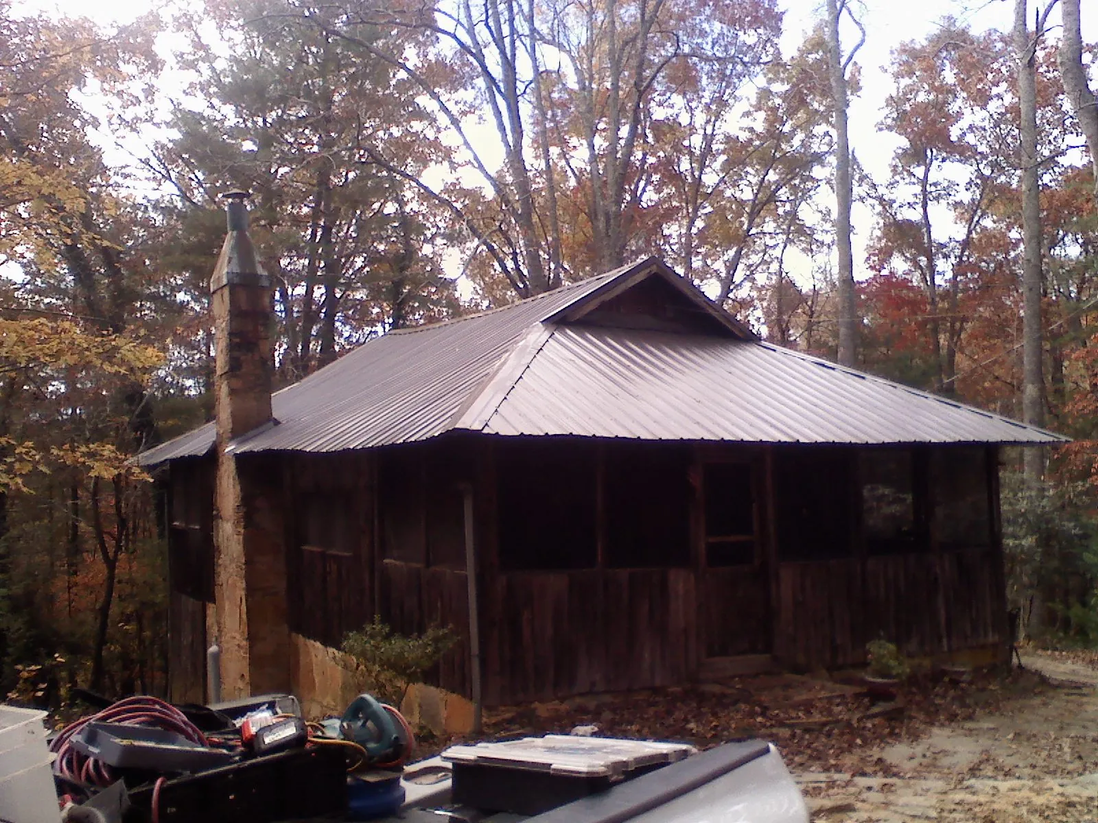 Brown metal hip roof on an old cabin with a stone chimney in Canajoharie