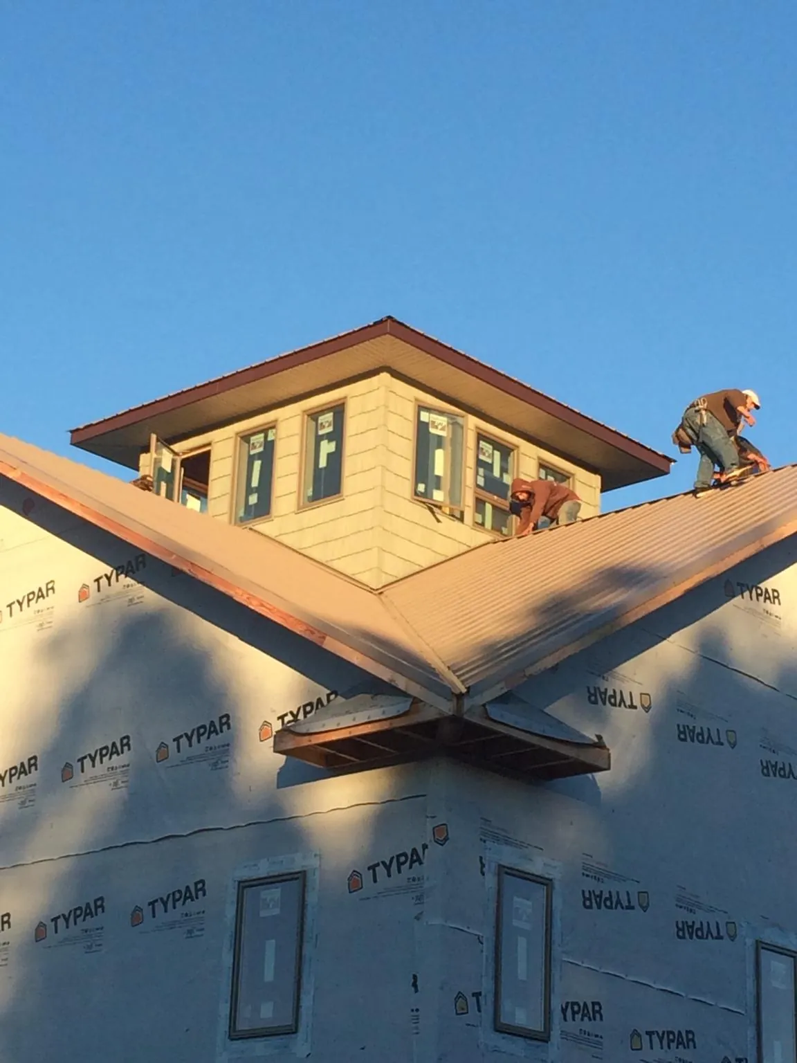 Roofers working around a rooftop cupola on a new metal roof at sunset — Roof Waterproofing in Canajoharie by Roofing Brothers